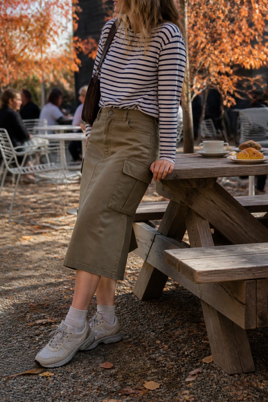 10 Fall Skirt Outfit Ideas for 2026 10 Model wearing a cargo skirt and striped tee at an outdoor café.
